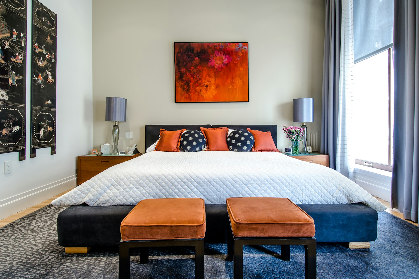 Bedroom with a blue rug and orange cushions