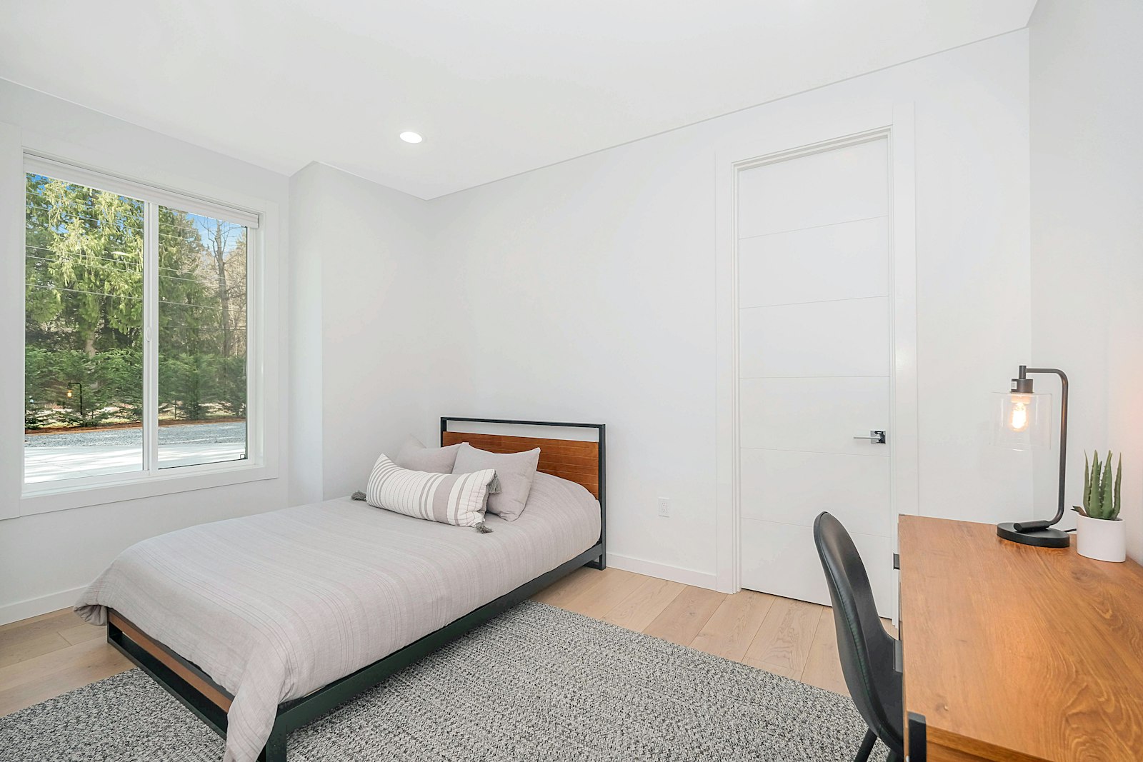 Plain single room with a bed and a desk lamp
